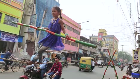Poor-little-Indian-girl-balancing-long-stick-and-walking-on-rope-as-street-performer,-people-watching,-Slow-motion