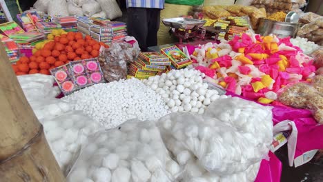 Indian-street-vendor-selling-many-Diwali-festival-sweets-at-market,-slow-camera-dolly-shot