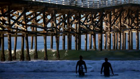Surfers-at-the-Crystal-Beach-Pier-in-San-Diego,-California