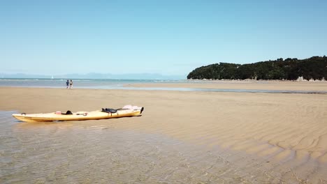 Sandy-Bay,-Abel-Tasman-National-Park,-New-Zealand,-Aerial-View-of-Couple-Walking-on-Beach-With-Kayak