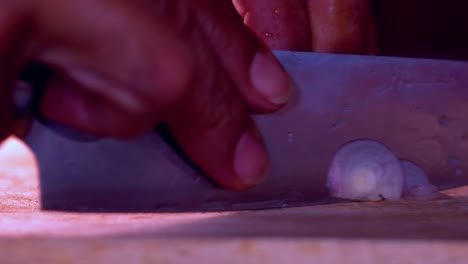 Cutting-a-red-onion-on-wooden-board-with-sharp-knife,close-up-slow-motion