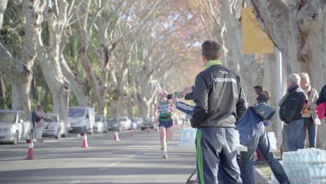 Volunteers-giving-water-to-runners-at-Malaga-marathon,-slow-motion,-Spain