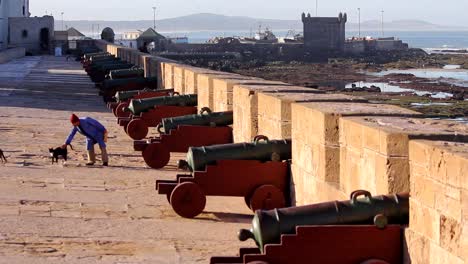 Panning-to-the-left-from-the-Atlantic-ocean-to-the-fishing-port-of-Essaouira,-Morocco-showing-the-crenelated-wall-and-canons