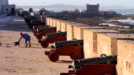 Panorámica-A-La-Izquierda-Desde-El-Océano-Atlántico-Hasta-El-Puerto-Pesquero-De-Essaouira,-Marruecos,-Mostrando-El-Muro-Almenado-Y-Los-Cañones