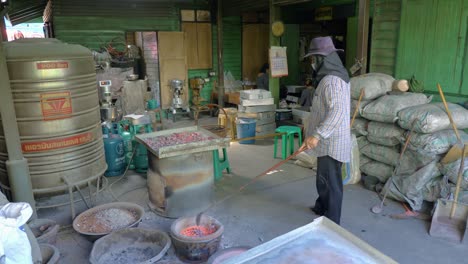 Man-scooping-burning-embers-with-long-ladle-and-placing-them-on-roasting-dish,-slow-motion