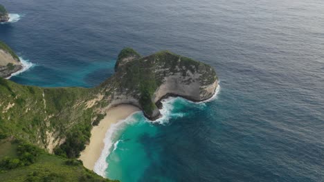 Aerial-POI-of-tropical-sandy-beach-nestled-in-lush,-green-cliffs