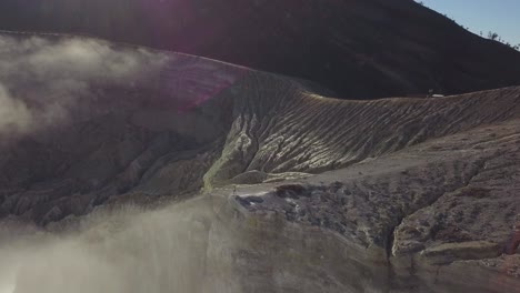 Toma-Aérea-Del-Cráter-Del-Volcán-En-Java,-Indonesia-Con-Un-Hombre-Parado-En-El-Borde-Del-Cráter-Después-De-Caminar