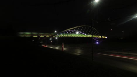 Steve-Prescott-bridge-Illuminated-timelapse-traffic-crossing,-St-Helens-Merseyside-speeding-vehicles-under-colourful-lit-bridge