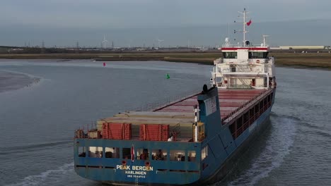 Aerial-tracking-shot-following-the-Peak-Bergen-ship-navigating-bouys-sailing-along-the-Swale-Estuary-towards-the-Sheppey-Crossing-in-Kent,-UK