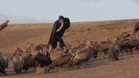 Group-of-men-herding-Griffon-vulture-birds-up-hillside-at-Tibetan-sky-burial-spiritual-ceremony