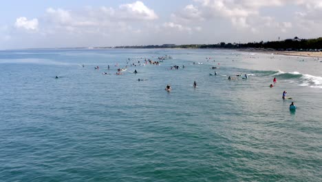 Surfers-waiting-for-large-waves-on-a-popular-international-surfing-spot,-Aerial-drone-flyover-shot