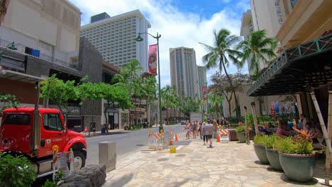 Gente-Caminando-Por-Un-Sendero-En-Hawaii-En-Un-Día-Soleado-Y-Autos-Pasando-Por-La-Calle