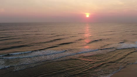 Pink,-purple-sunrise-over-the-ocean-,Pulling-backwards-slowly-revealing-beach