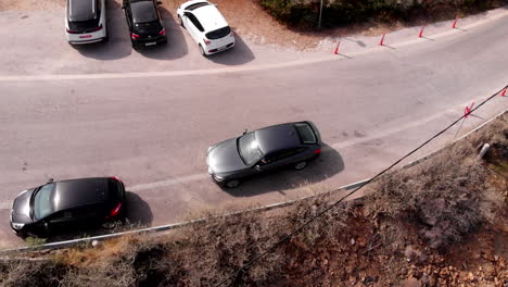 BMW-car-on-side-of-road-driving-away-in-Greece,-aerial-tracking-flyover-shot