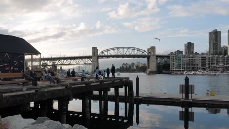 Vancouver,-Kanada:-Zeitraffer-Sonnenuntergang-An-Der-Burrard-Street-Brücke-In-Der-Nähe-Des-Granville-Marktes-In-Vancouver,-Kanada,-Mit-Sonnenuntergang-Und-Vielen-Menschen-Beim-Picknick-Auf-Dem-Pier
