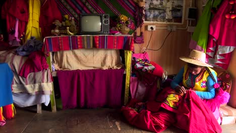 inside-peruvian-hut,-indigenous-is-weaving-clothes,-slow-right-panning-camera-movment