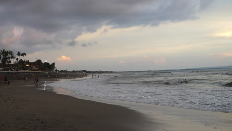 Bali-tourists-enjoying-the-beach-and-mild-ocean-waves-at-sunset