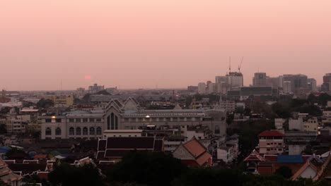Timelapse-of-hazy,-orange-sunset-over-city-of-Bangkok,-Thailand