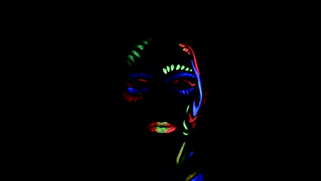 Close-up-of-a-girl's-face-in-ultraviolet-bodypaint-opening-her-eyes-and-looking-into-the-camera