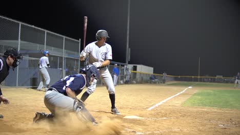 Slow-motion-clip-of-a-minor-league-baseball-batter-receiving-a-low-pitch-at-a-night-game