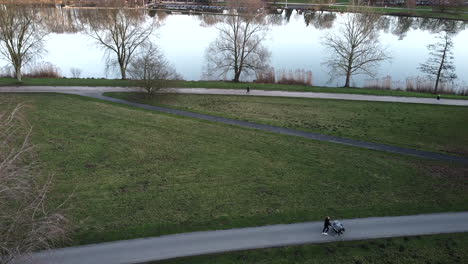 Aerial-shot-showing-walking-and-jogging-people-on-path-beside-beautiful-lake-during-autumn