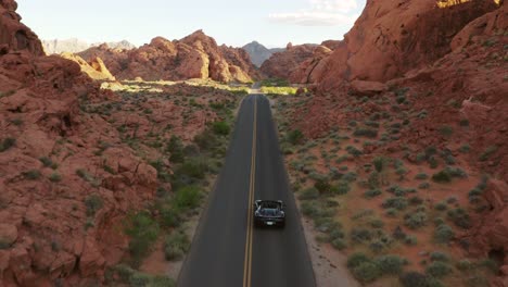 Black-Ferrari-convertible-speeding-through-the-canyons-of-the-Valley-of-Fire,-Nevada