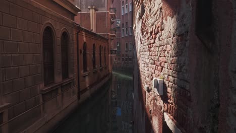 Water-taxi-passing-through-the-narrow-channel-in-Venice,-Italy