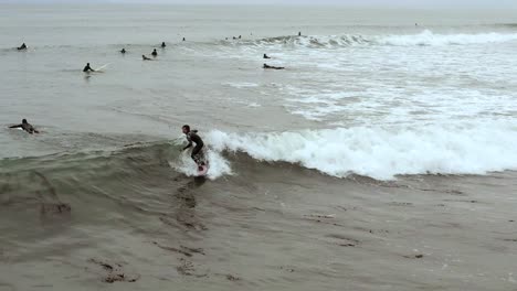 Aerial-view-tracking-skilled-surfers-riding-waves-at-Ventura-Beach