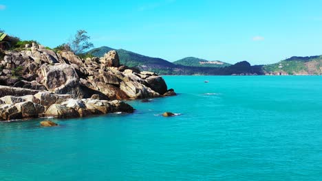Beautiful-cliffs-washed-by-azure-sea-water-on-coastline-of-tropical-island-with-green-hills-under-bright-blue-sky-in-Thailand