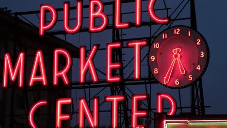 A-close-up-shot-of-the-neon-sign-at-Public-Market-Center-in-Seattle-Washington-against-a-dark-moody-sky,-birds-in-the-background