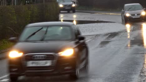 Cars-splashing-huge-wave-on-stormy-flash-flooded-road-corner-bend-UK