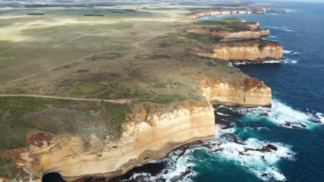 Wide-aerial-of-huge-cliffs-and-patches-of-sun-on-farmland-in-Australia