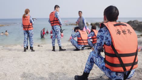 Xiaoliuqiu-group-sitting-waiting-in-camo-inflatable-lifeguard-jackets-to-explore---swim-with-turtles