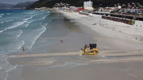 Ein-Raupen-Bulldozer-Mit-Schweren-Maschinen-öffnet-Einen-Durchgang,-Durch-Den-Wasser-Aus-Dem-Naturschutzgebiet-Zandvlei-Mündung-In-Den-Muizenberg-Strand-Fließen-Kann