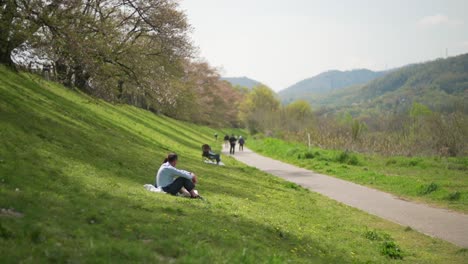 Japanisches-Paar,-Das-Auf-Dem-Grünen-Gras-Sitzt-Und-Unter-Dem-Sakura-Baum-Am-Sewaritei-Staudamm-In-Kyoto,-Japan,-Kühlt---Totale