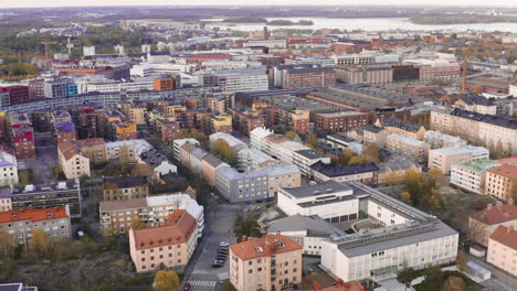 Aerial,-tracking,-drone-shot-tilting-towards-houses-and-buildings,-in-the-Alppila-area-of-Helsinki,-cloudy,-spring-evening,-in-Uusimaa,-Finland