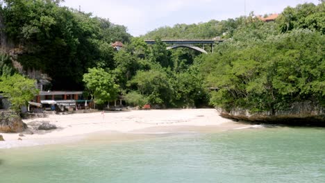 La-Playa-De-Padang-Padang-Con-El-Puente-Labuansait,-Vista-Panorámica-Derecha-Aérea-Revelada