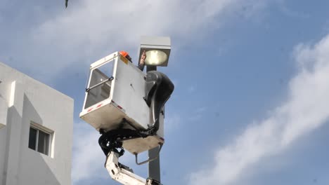 Municipal-service,-worker-on-height-in-hydraulic-lift-basket-repairs-street-lamp