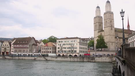 Heart-of-Zurich-old-town,-iconic-Grossmunster-Cathedral-towers,-Limmat-riverbank