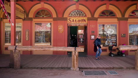 A-female-tourist-walking-out-of-the-famous-Big-Nose-Kate-Saloon-in-the-wild-west-theme-park-of-Tombstone,-Arizona---slow-pan