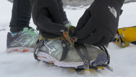 Close-Up-of-Gloved-Hands-Strapping-on-Crampons,-Gearing-up-for-a-Glacier-Hike