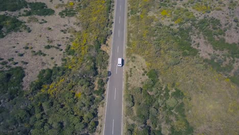 Aerial-top-down-view-of-white-car-driving-on-straight-country-road