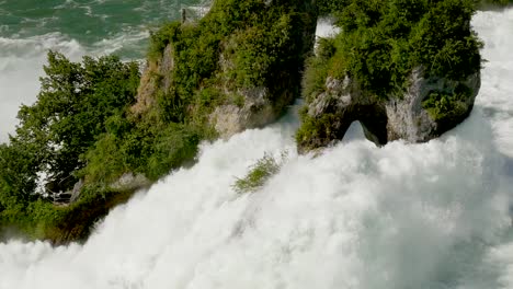 Tilt-up-close-up-shot-of-giant-waterfall-dashing-against-rock-of-rhine-fall-during-sunny-day