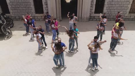 Group-of-adult-male-and-female-Caucasian-dancers-practice-authentic-salsa-in-outdoor-square-in-Dhour-el-Choueir,-Lebanon,-overhead-aerial-descend