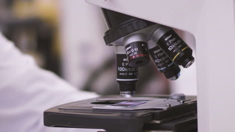 Wissenschaftler-Legt-Einen-Probenträger-Zur-Untersuchung-Unter-Ein-Mikroskop