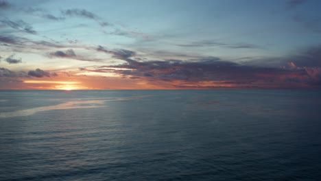 Beautiful-glowing-golden-sunset-beyond-the-calm-blue-ocean-in-Fiji---wide-shot