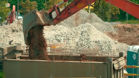 Close-up-view-of-excavator-bucket-loading-the-soil-into-a-dump-truck