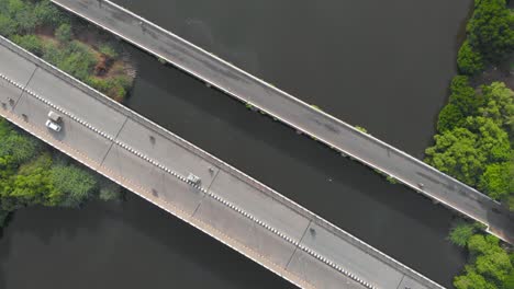 Top-Down-Aerial-shot-of-vehicles-moving-along-with-the-two-bridges-connecting-two-sides-of-the-land-been-separated-by-a-river-shot-with-a-drone-in-4k