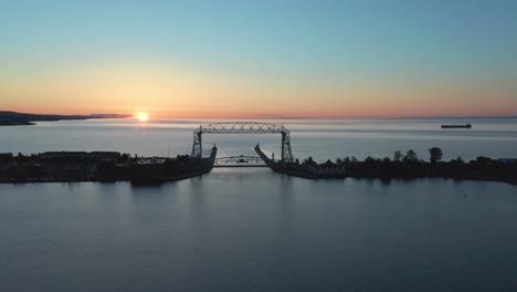 Aerial-view-of-Lift-Bridge-over-harbor-at-sunset---drone-flying-shot-of-Lake-Superior-Duluth,-Minnesota