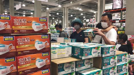 Japanese-Family-Looking-And-Checking-The-Boxes-Of-Masks-Before-Buying-Them-During-The-Coronavirus-Outbreak-In-Tokyo,-Japan